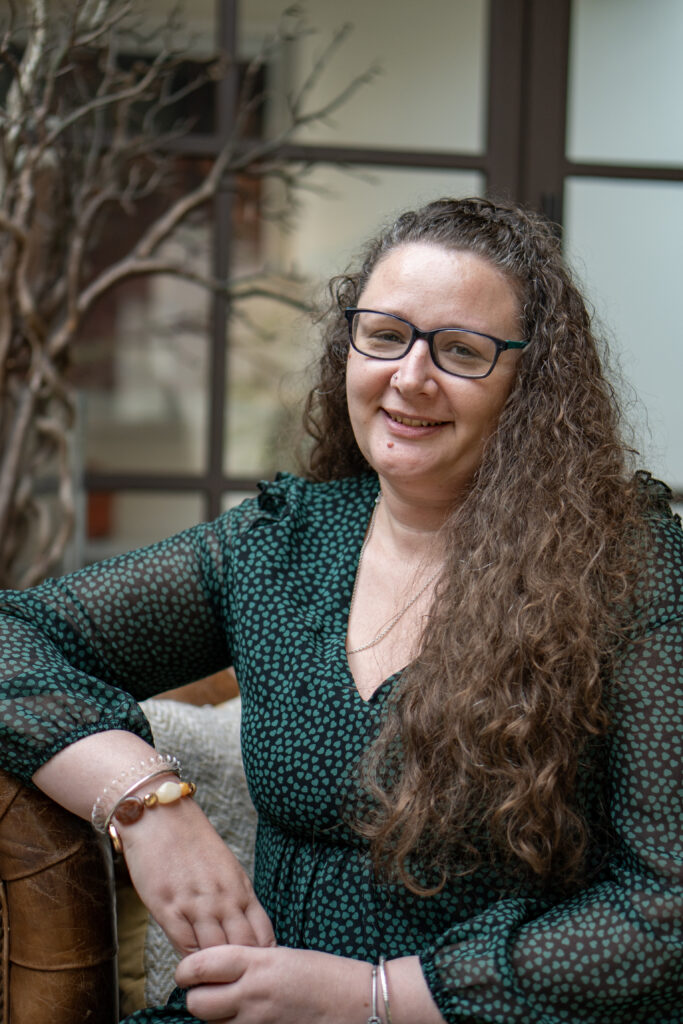 Jo Scavuzzo-Ramsey, trauma-informed counsellor in Banbury, smiling and seated on a leather sofa